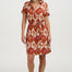 Woman wearing a patterned dress with a plain background