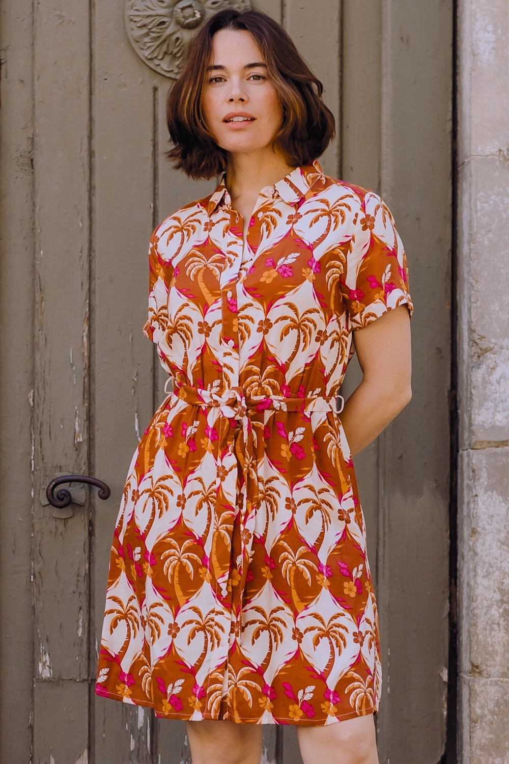 Woman wearing a patterned dress standing in front of a door.