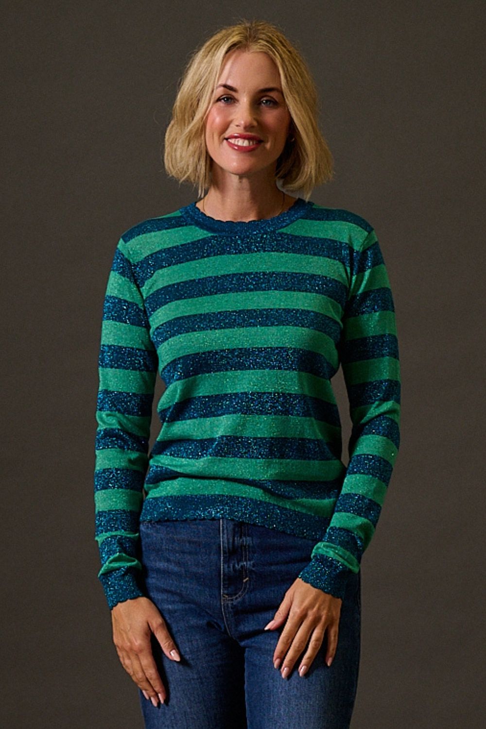 Woman wearing a green and blue striped sweater against a brown background