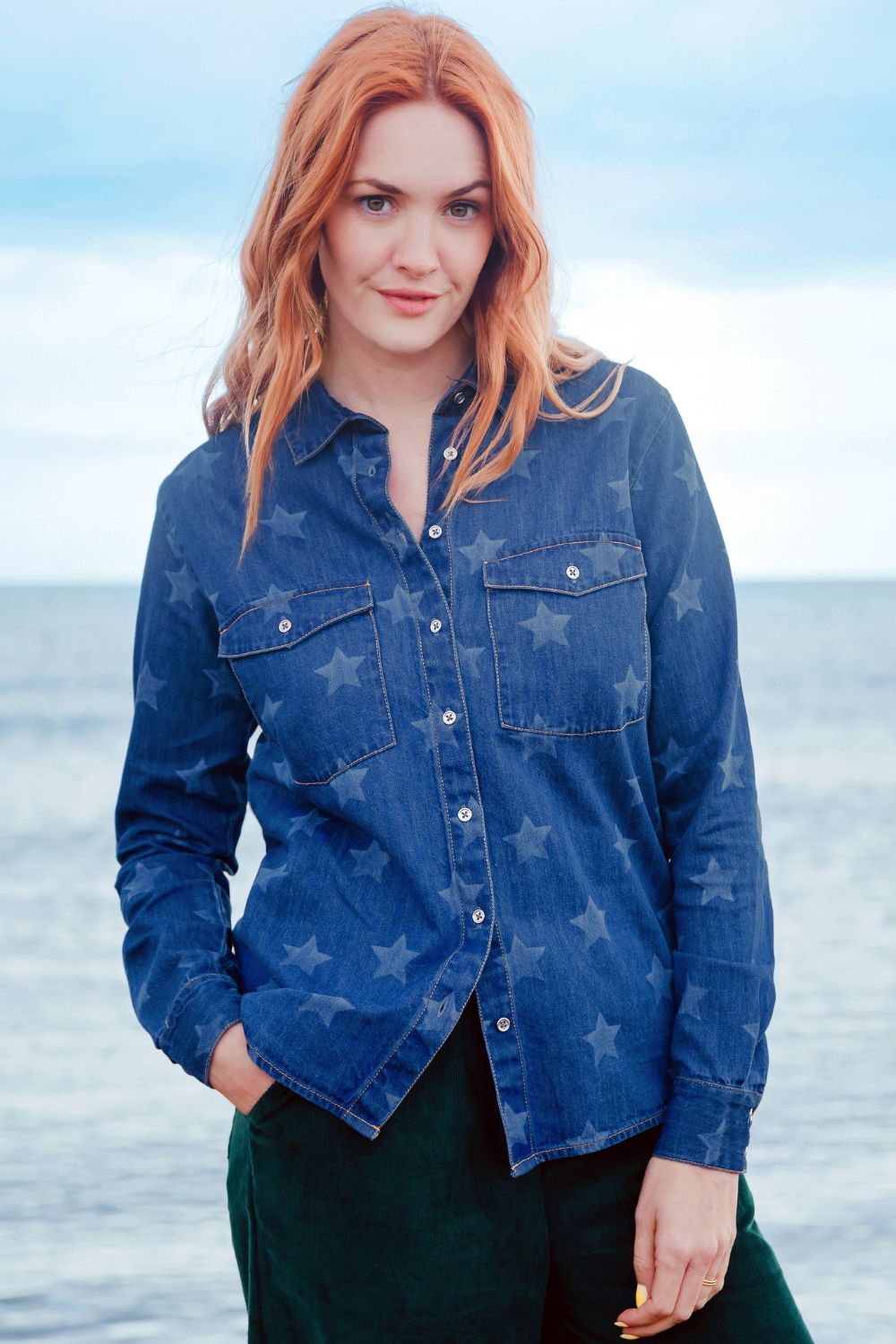 Woman wearing a blue denim shirt with star patterns on a beach