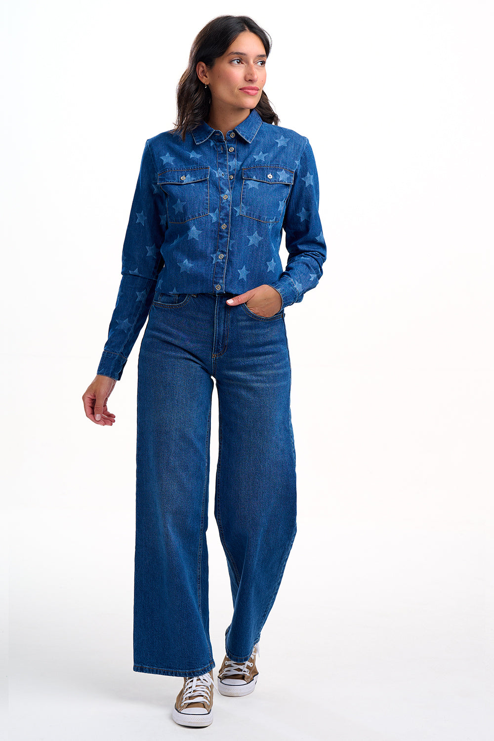 Woman wearing a blue denim outfit with star pattern on a white background