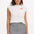 A woman wearing a classic mini skirt with monochrome pinstripes in black and white. She is also wearing a white top with a visible logo on the chest.