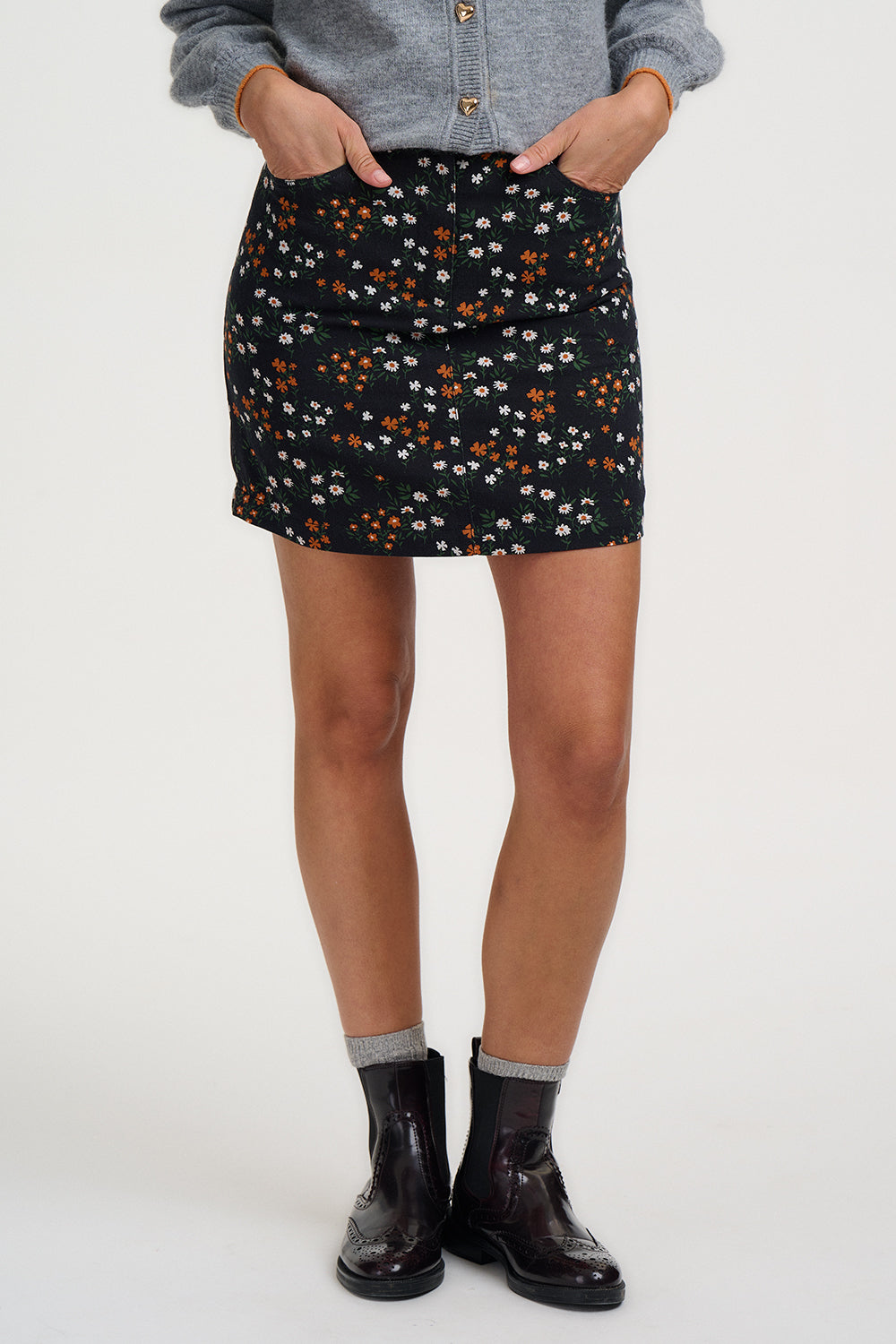 Person wearing a black floral skirt with a plain background