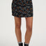 Person wearing a black floral skirt with a plain background