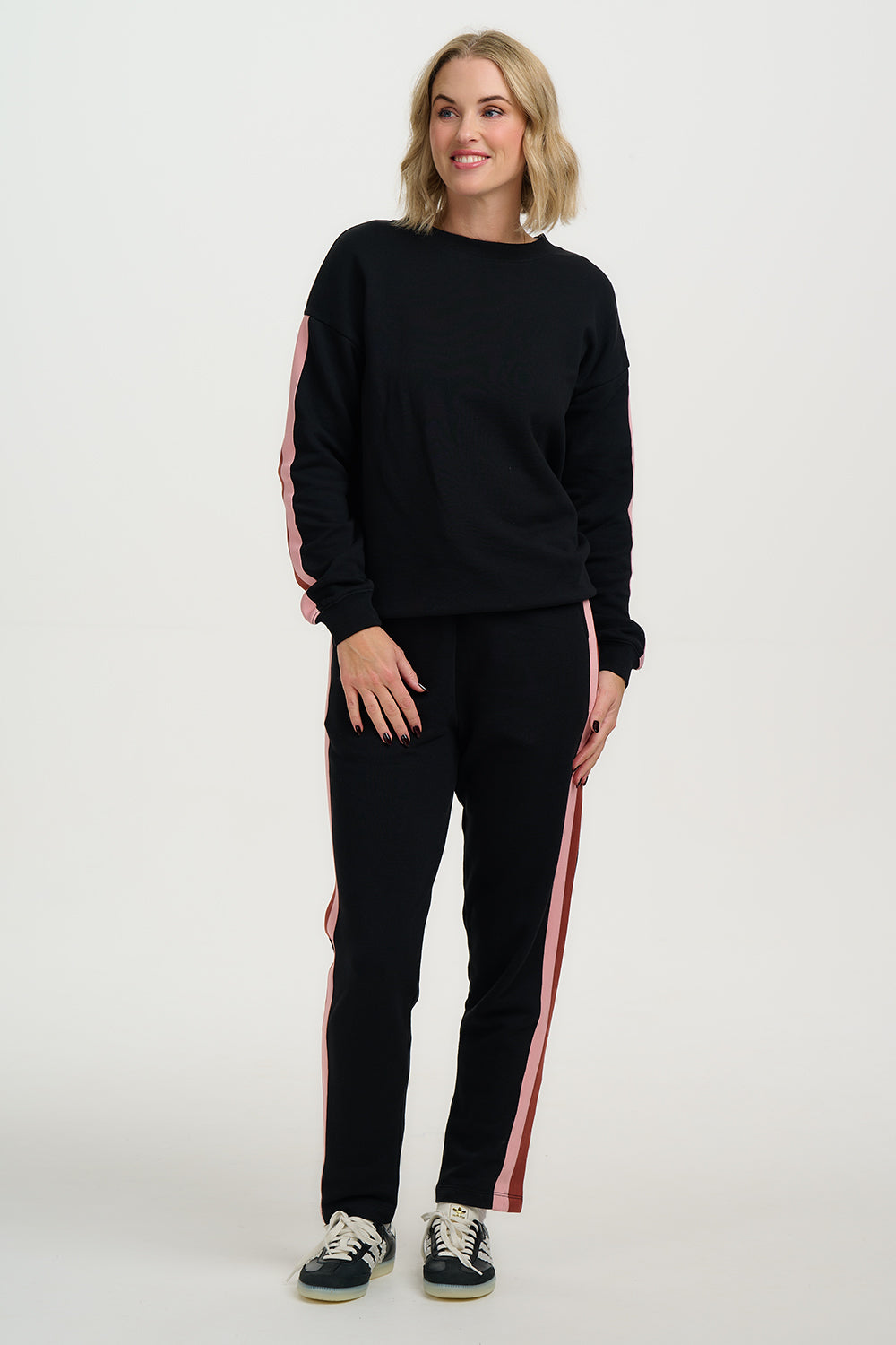 Woman wearing a black tracksuit with red stripes on a white background
