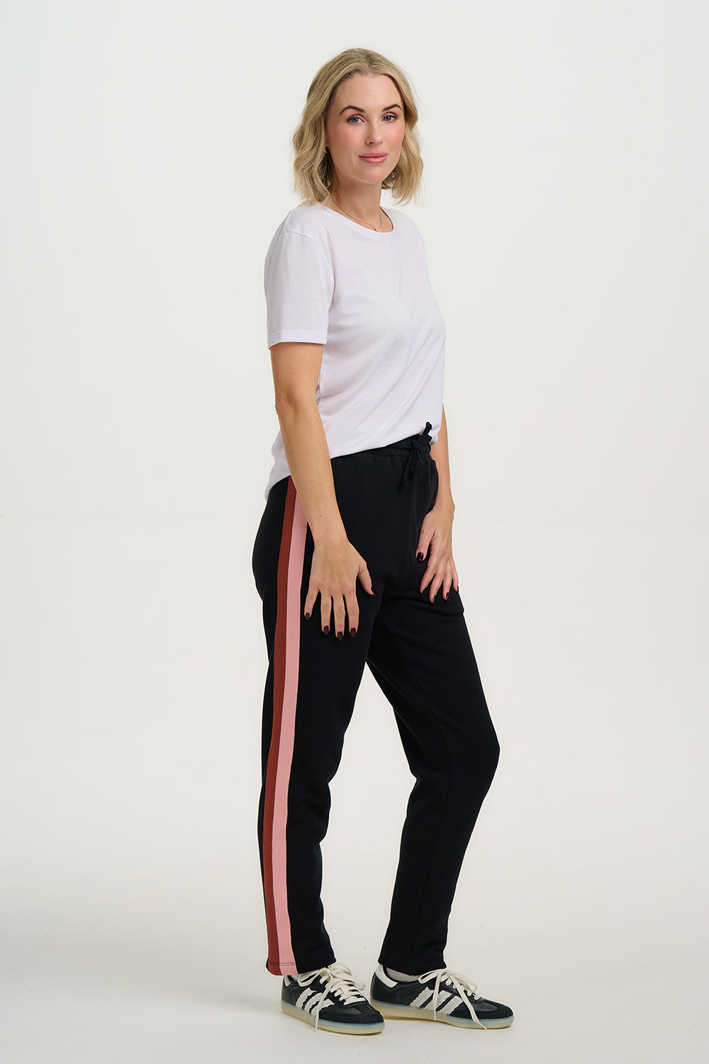 Woman wearing a white t-shirt and black pants with red stripes on a white background