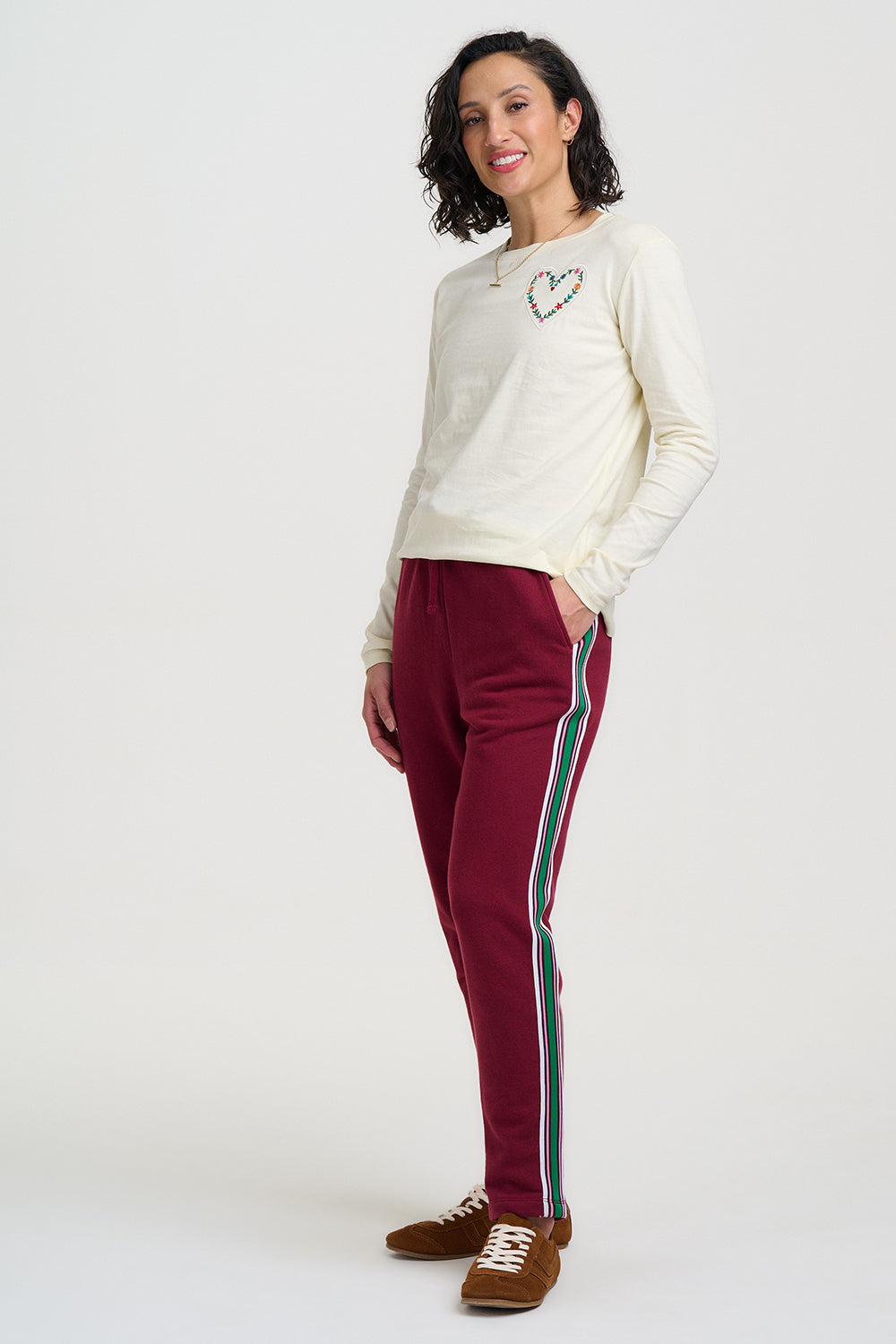 Woman wearing burgundy pants with white stripes on a white background