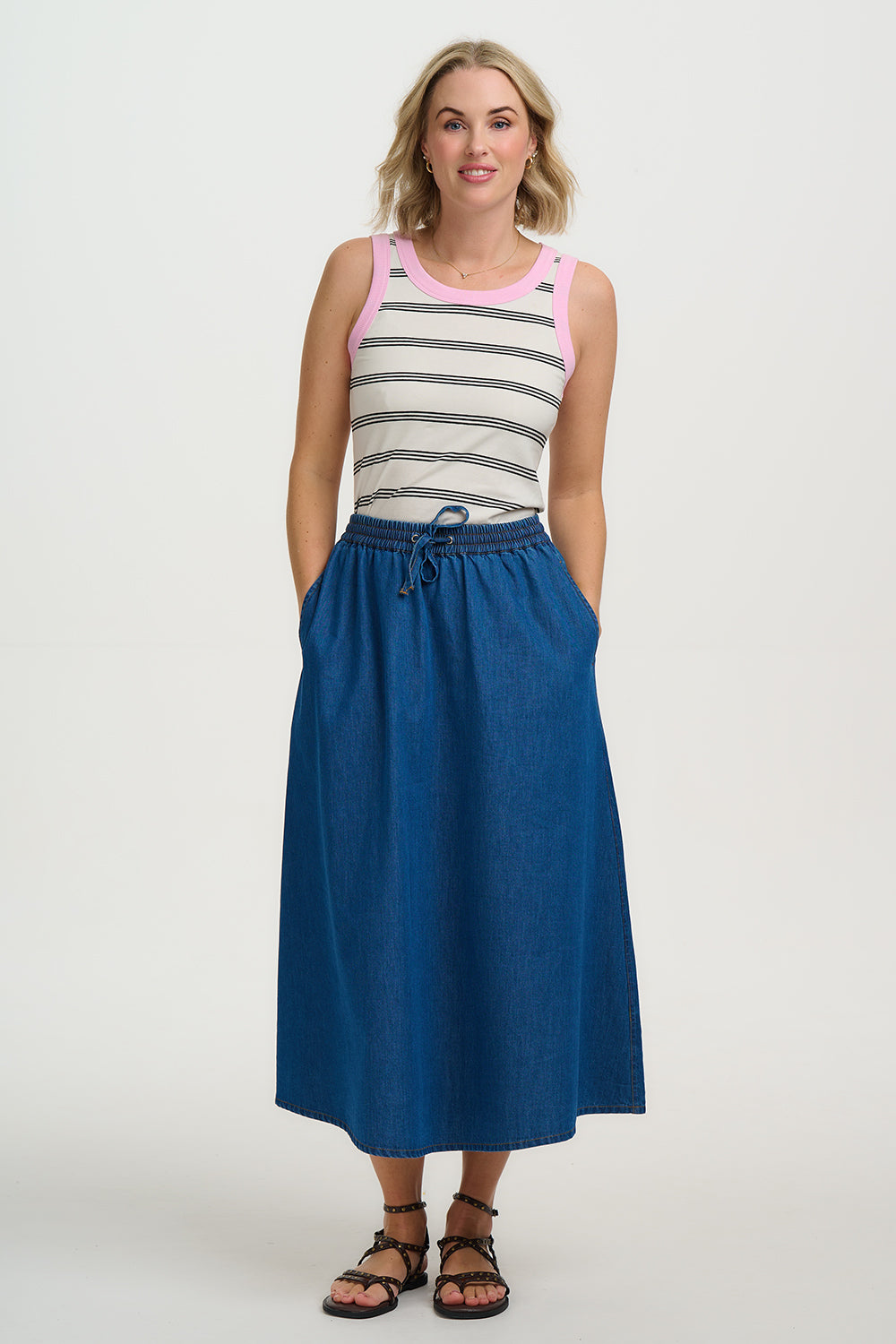Woman wearing a striped tank top and blue skirt on a white background