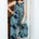 Woman wearing a patterned jumpsuit standing in a doorway.