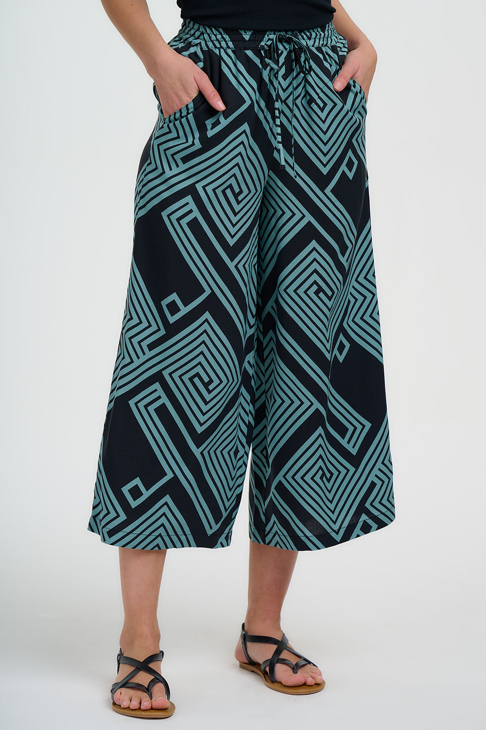 Person wearing black and teal patterned wide-leg pants on a white background