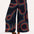 A model wearing black cropped wide-leg trousers with a geometric multicolour pattern, paired with a black tank top.