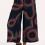 A model wearing black cropped wide-leg trousers with a geometric multicolour pattern, paired with a black tank top.