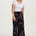 A model wearing black cropped wide-leg trousers with a geometric multicolour pattern, paired with a white top.
