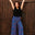 Woman in black top and colorful pants standing against a wooden door