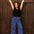 Woman in black top and colorful pants standing against a wooden door