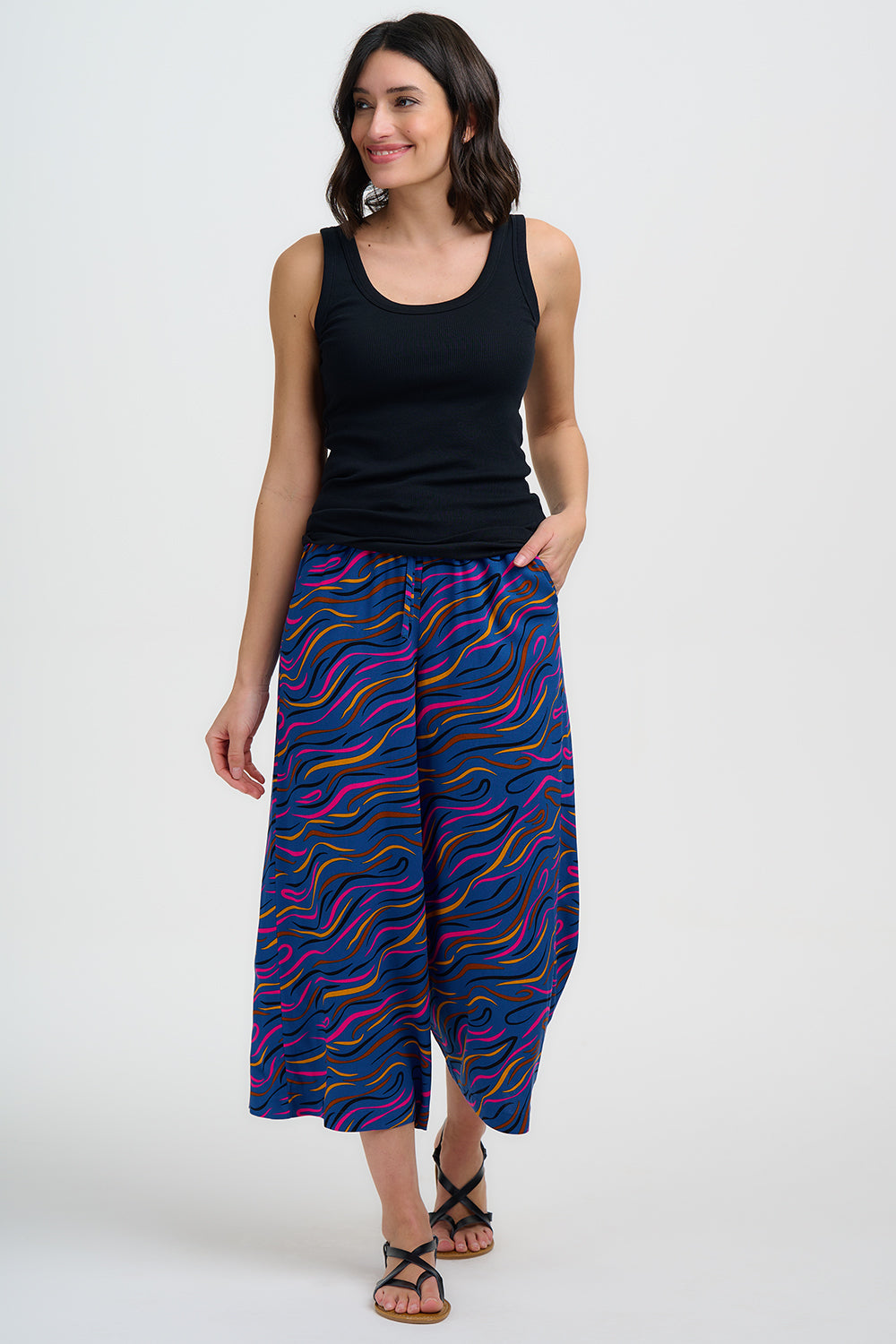 Woman wearing a black tank top and colorful wide-leg pants on a white background