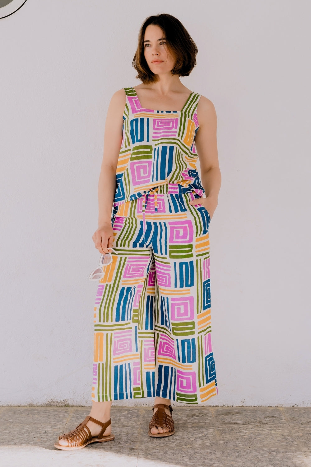 Woman wearing a colorful geometric patterned jumpsuit against a plain background