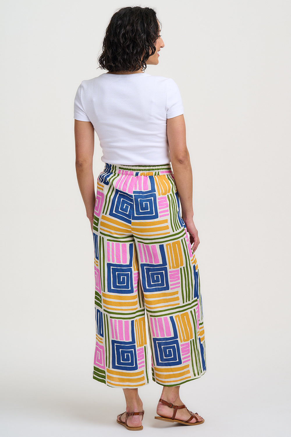 Person wearing colorful geometric-patterned pants on a white background