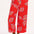 A model wearing red cropped wide-leg trousers with a colorful leaf pattern, standing against a white background.