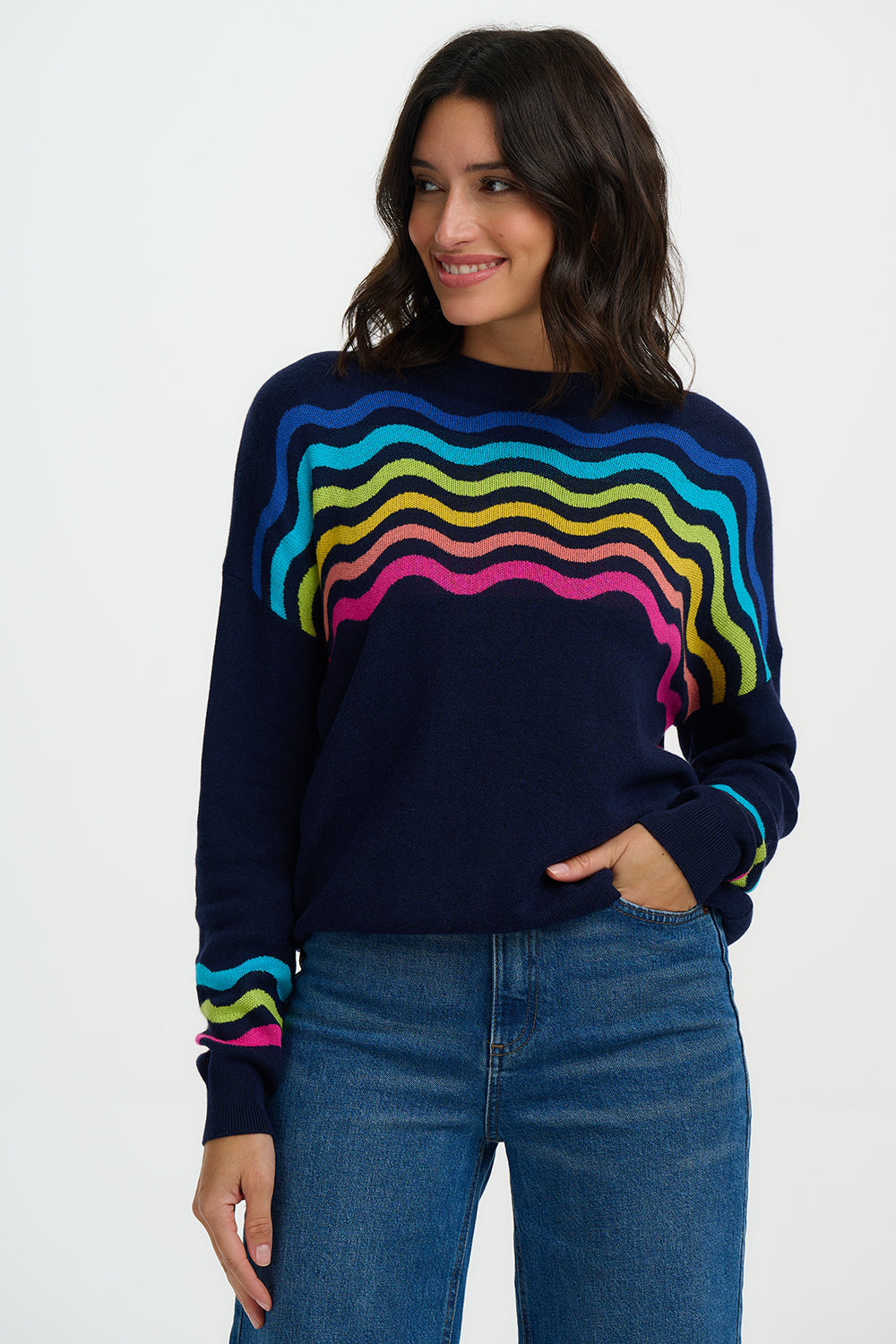 Woman wearing a navy sweater with colorful wavy pattern on a white background