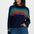 Woman wearing a navy sweater with colorful wavy pattern on a white background