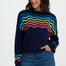 Woman wearing a navy sweater with colorful wavy pattern on a white background