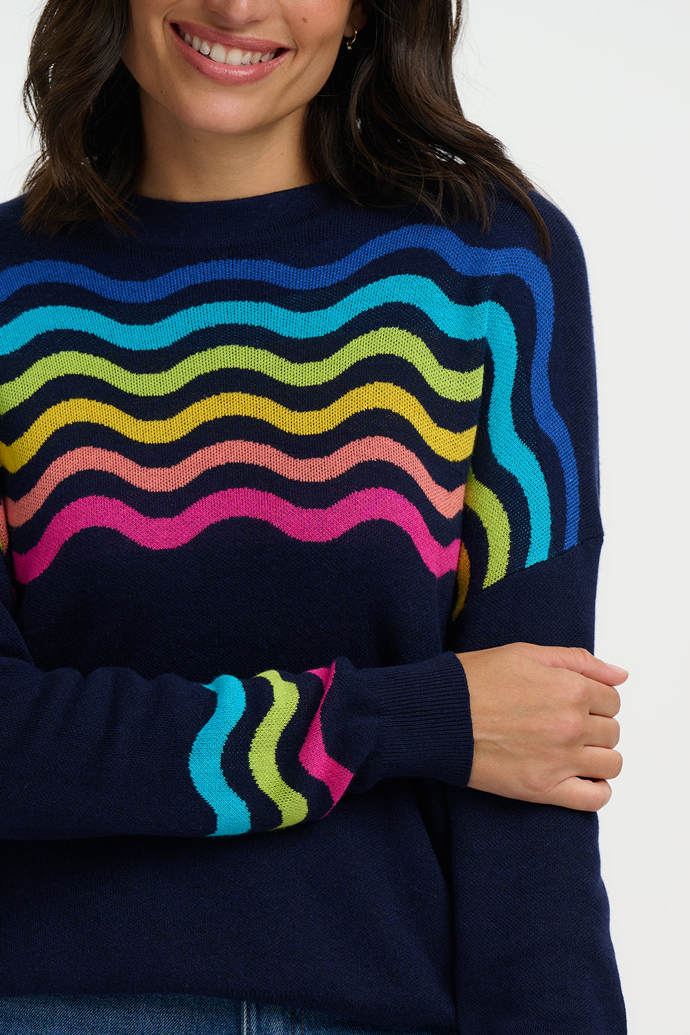 Person wearing a navy sweater with colorful wavy patterns on a white background