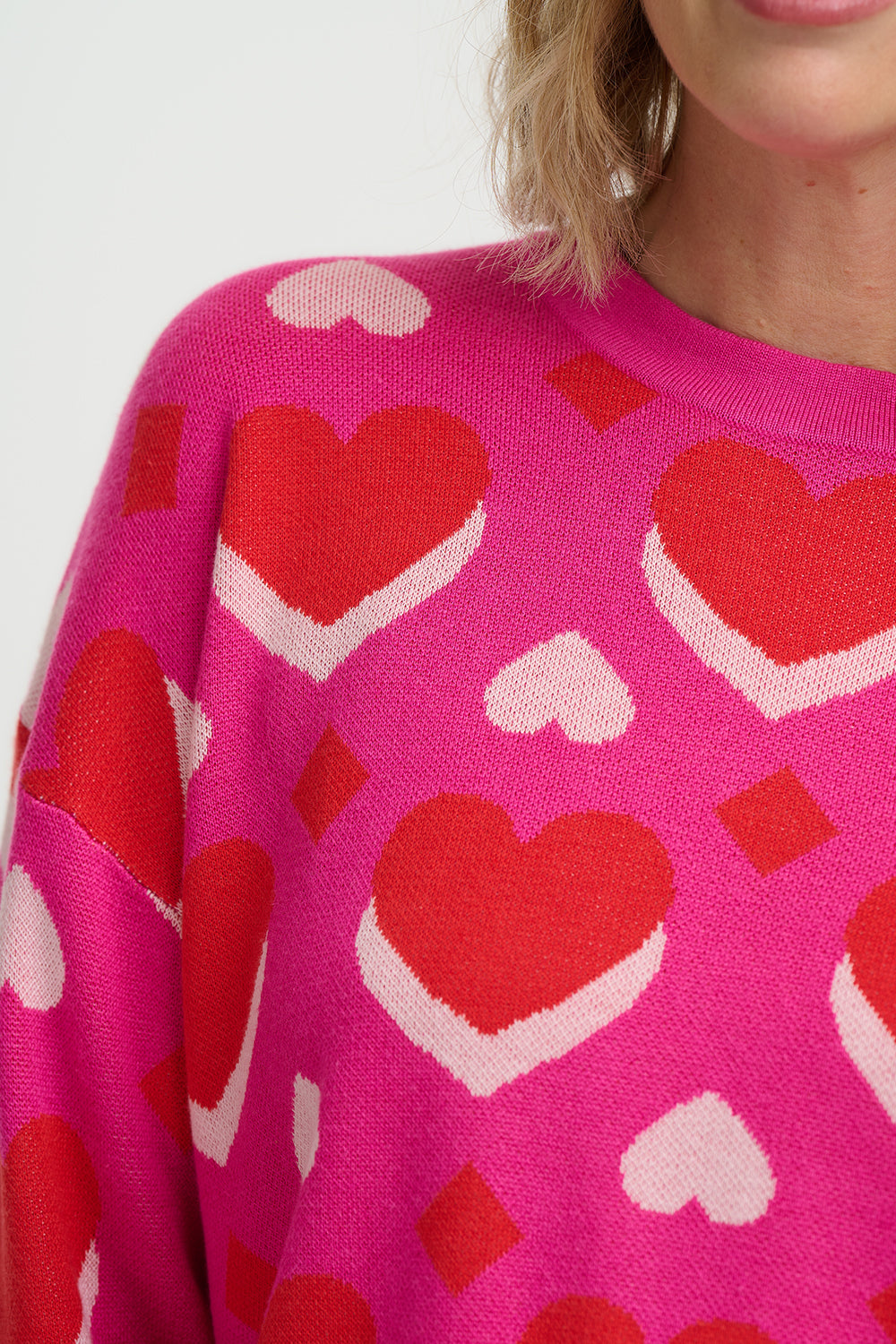 Pink sweater with red heart pattern on a white background