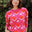 Person wearing a pink sweater with red heart patterns against a natural background