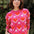 Person wearing a pink sweater with red heart patterns against a natural background