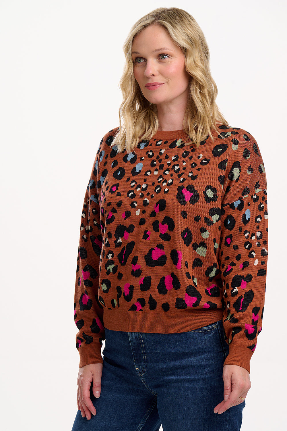 Woman wearing a brown sweater with colorful leopard print pattern on a white background