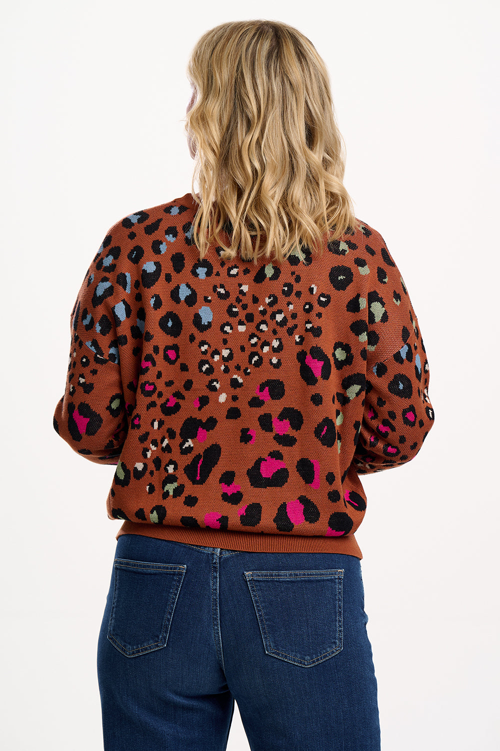 Person wearing a brown sweater with a colorful leopard print pattern on a white background