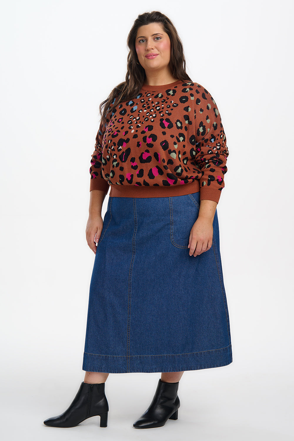 Woman wearing a leopard print top and blue skirt on a white background