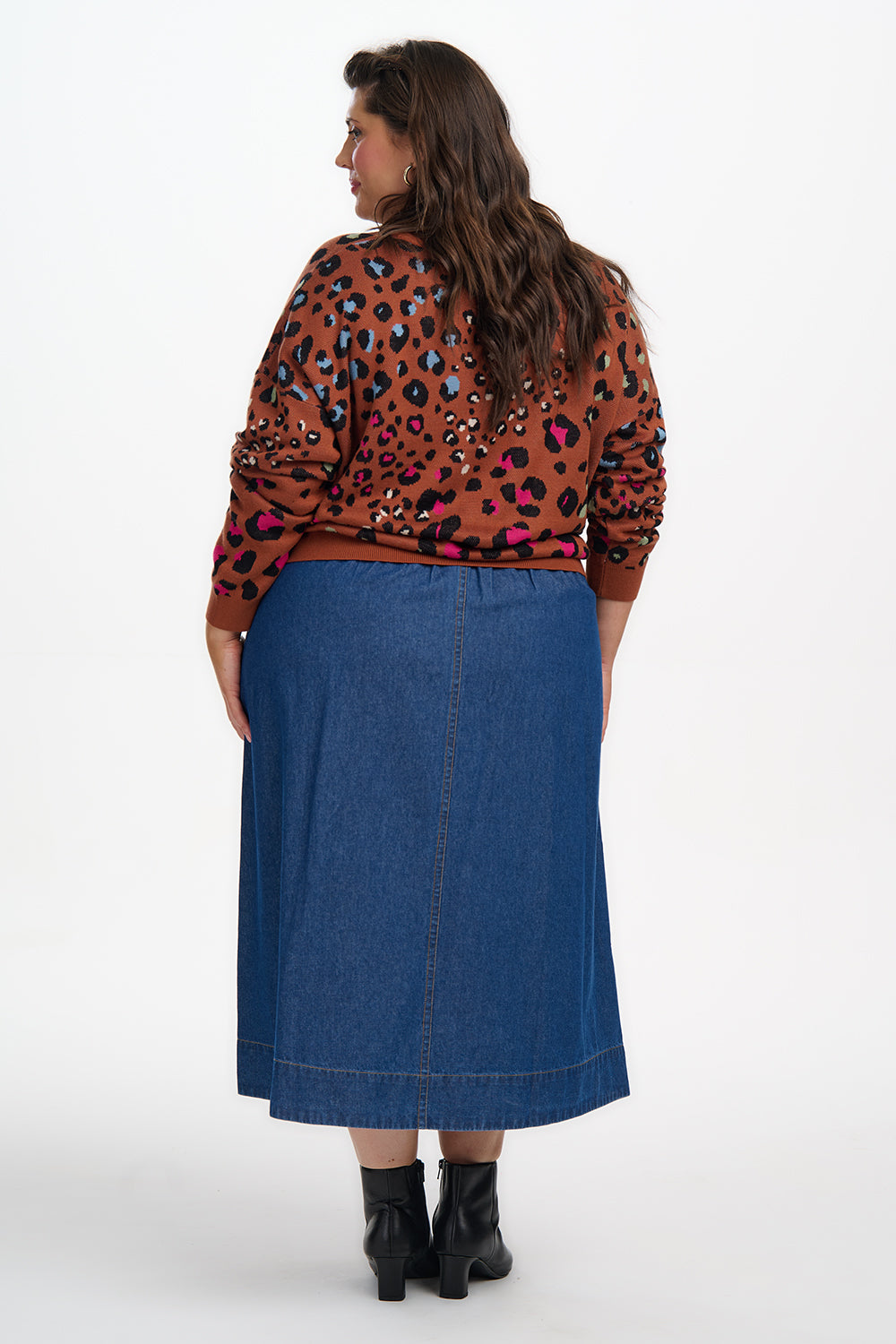 Woman wearing a leopard print top and blue skirt on a white background