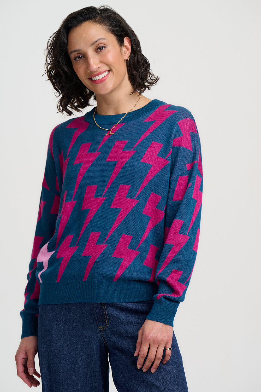 Woman wearing a blue sweater with pink lightning bolt pattern on a white background