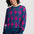 Woman wearing a blue sweater with pink lightning bolt pattern on a white background