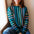 Woman wearing a colorful striped sweater sitting by a window.