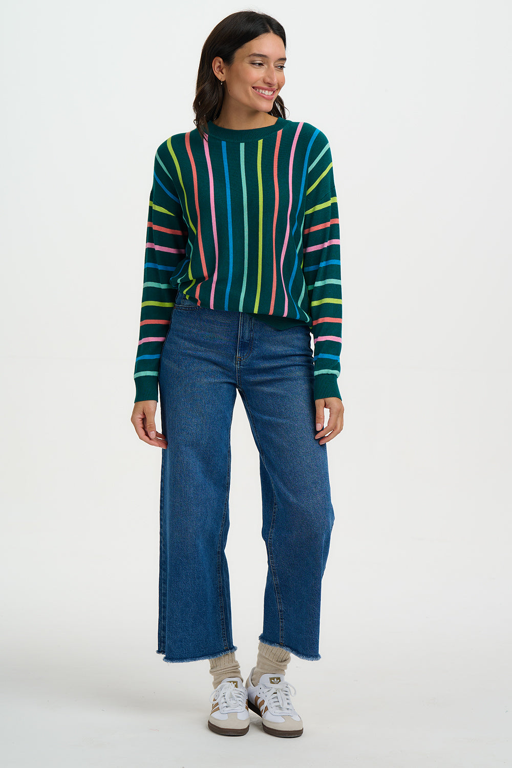 Person wearing a colorful striped sweater and blue jeans on a white background
