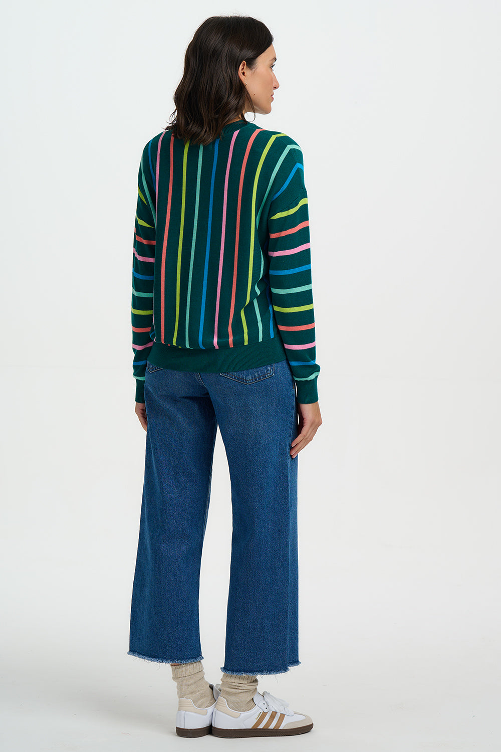 Person wearing a colorful striped sweater and blue jeans on a white background