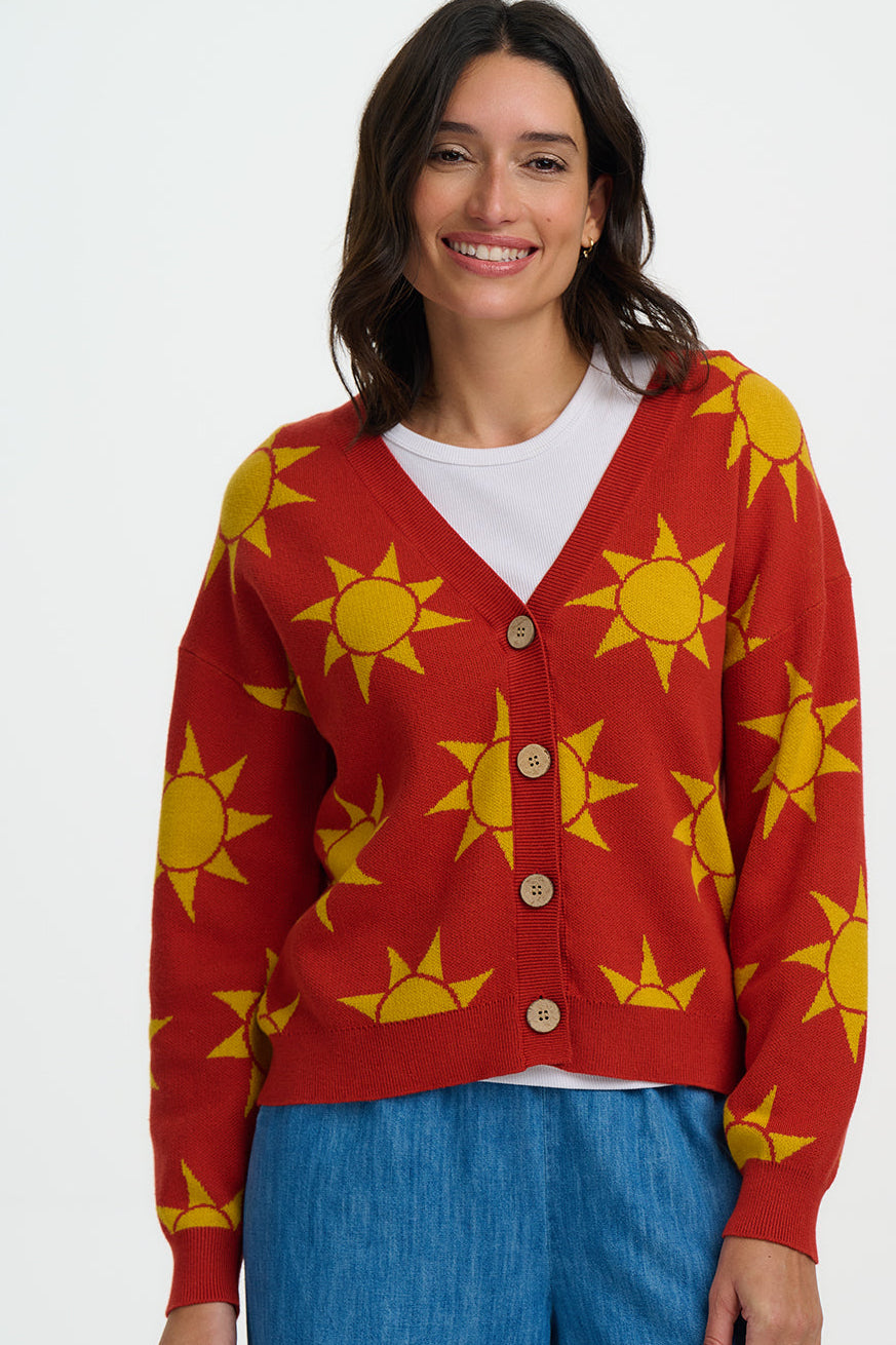 Woman wearing a red cardigan with yellow sun patterns on a white background