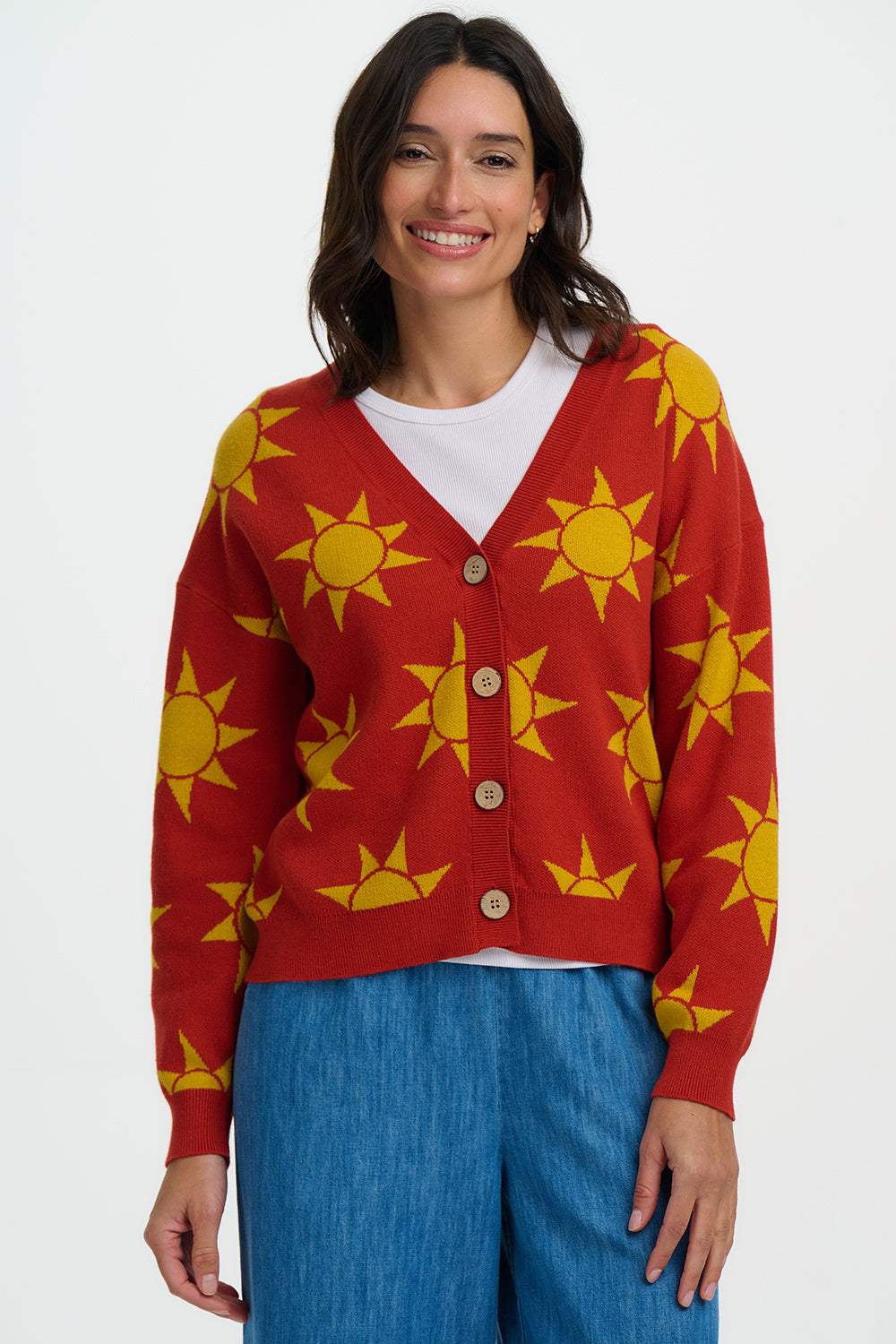 Woman wearing a red cardigan with yellow sun patterns on a white background