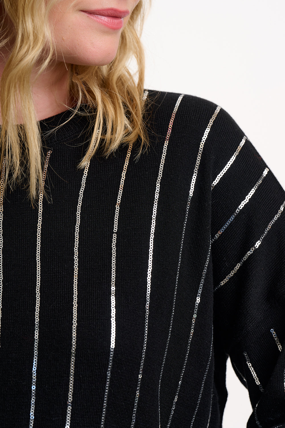 Black sweater with silver vertical stripes worn by a person