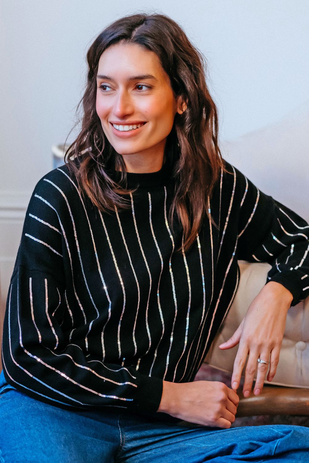 Woman wearing a black and white striped sweater sitting on a couch.