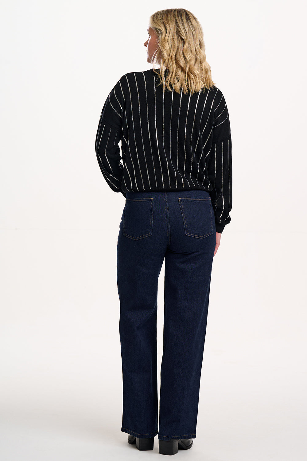 Woman wearing a black and white striped shirt and dark blue jeans on a white background