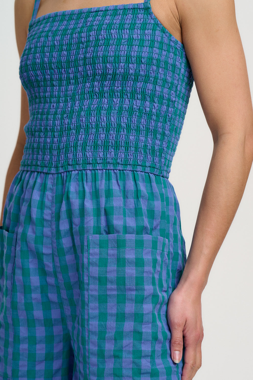 Green and blue checkered jumpsuit worn by a person on a plain background