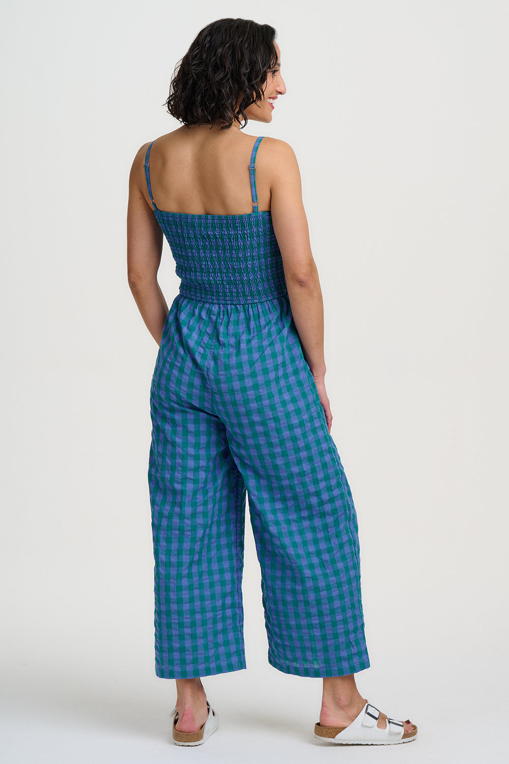 Woman wearing a blue checkered jumpsuit on a white background