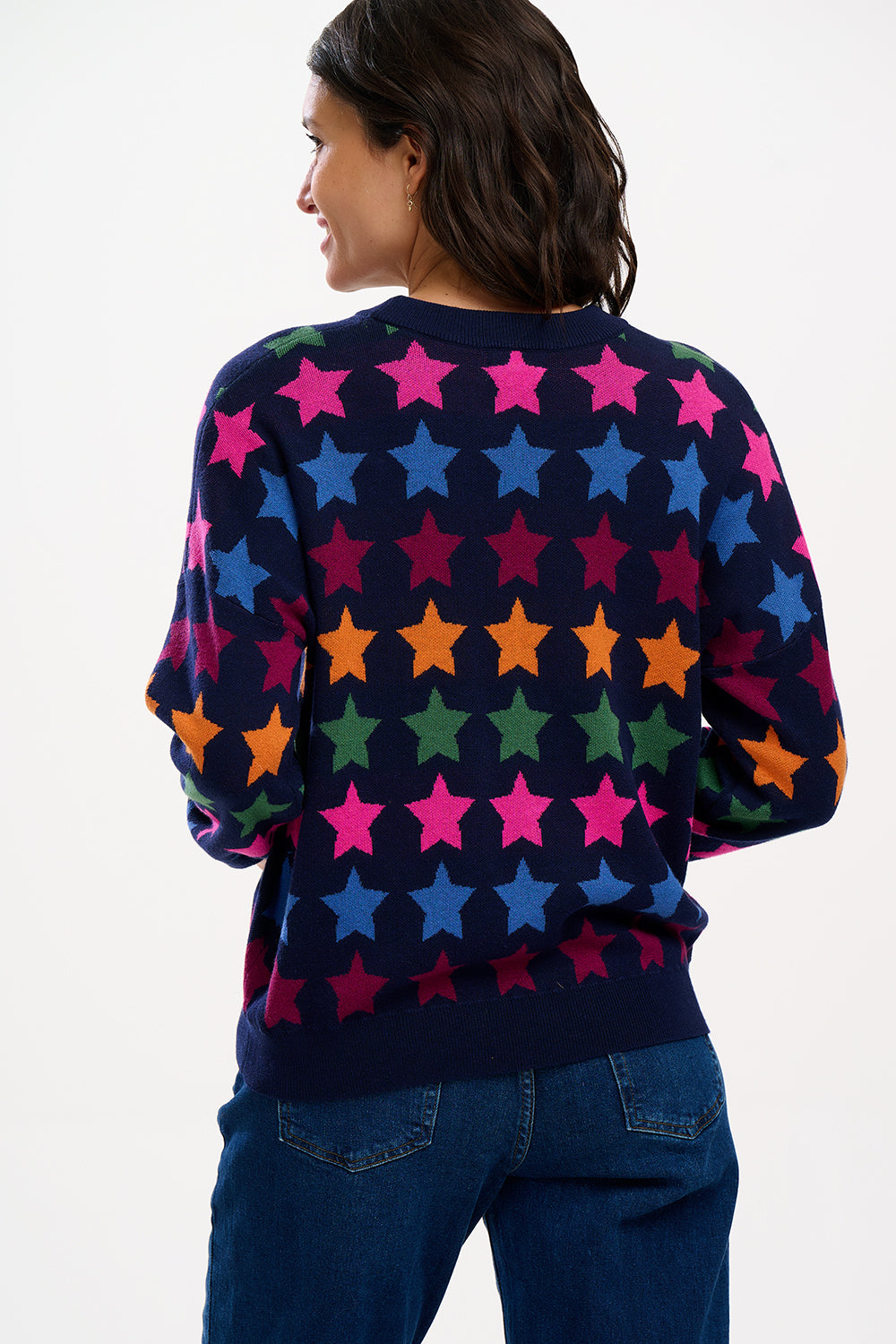 A woman wearing a multicolored star-patterned jumper with a round neckline and long sleeves.