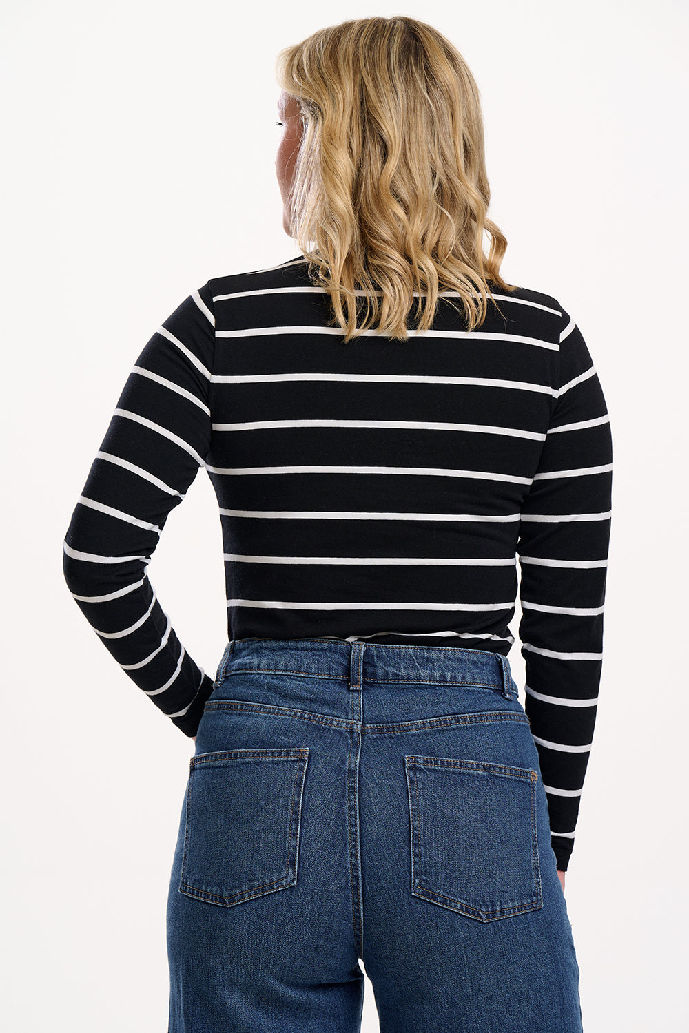 Sugarhill Brighton Sugarhill Brighton Annika Jersey Top - Black/White, Stripe Lightning. Woman wearing a black and white striped sweater with a lightening bolt logo with blue jeans on a white background