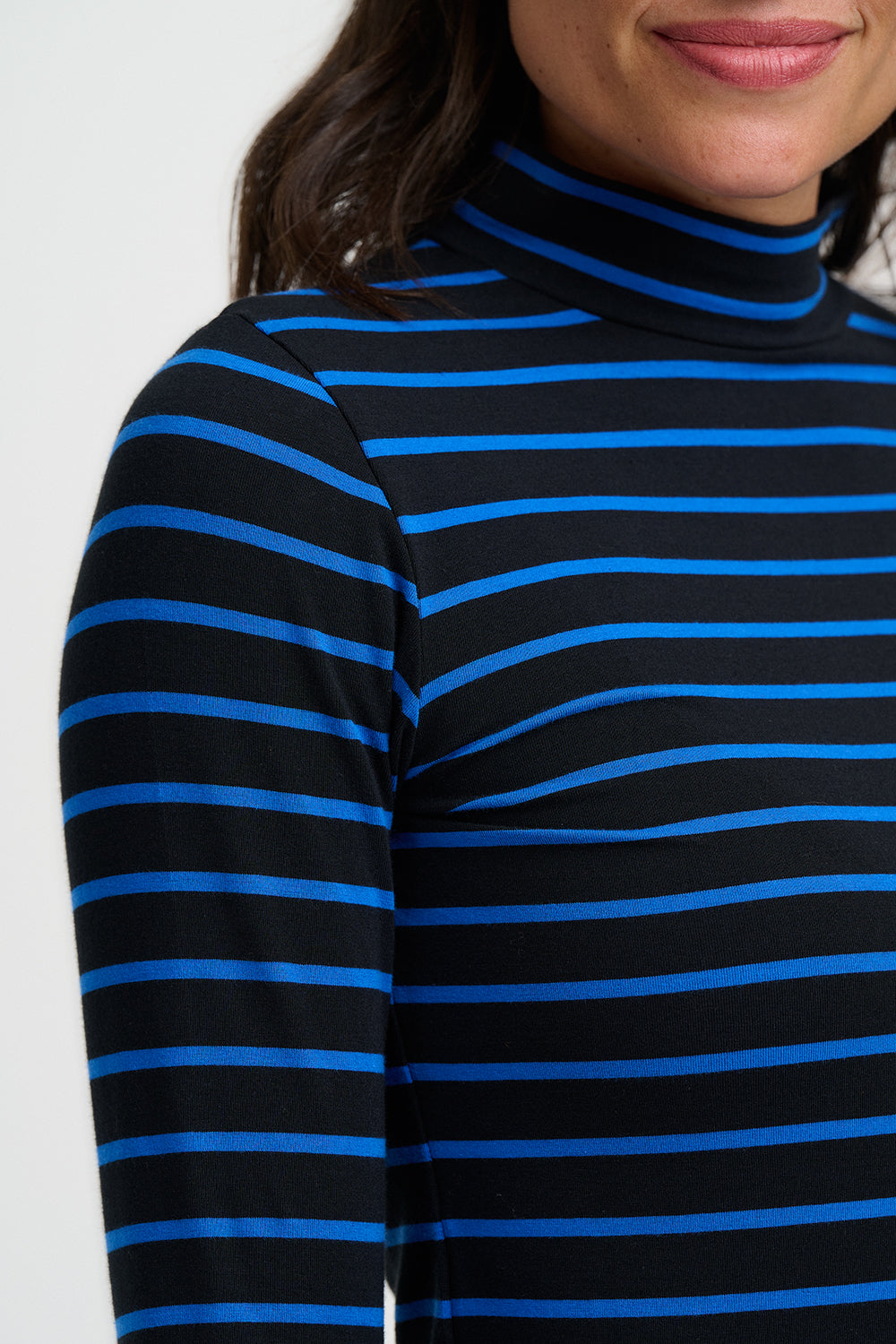 Black and blue striped long-sleeve top worn by a person on a white background