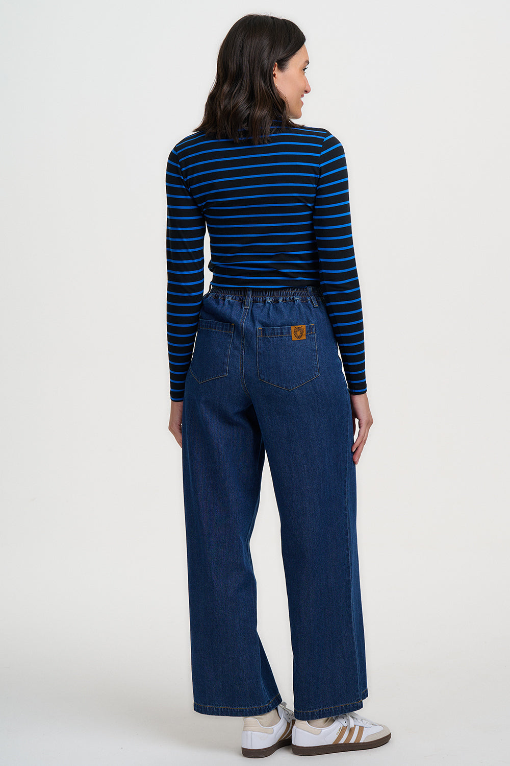 Person wearing a blue and black striped shirt and blue jeans on a white background